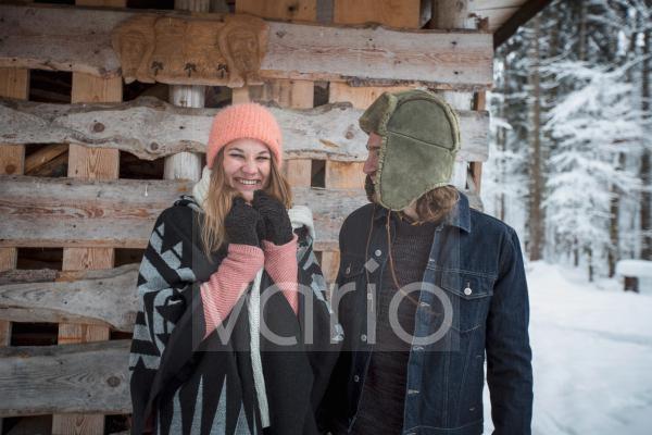 Portrait of happy couple in front of wood pile outdoors in winter